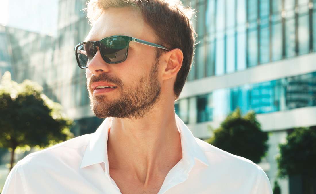 Muškarac u beloj košulji nosi moderne muške naočare za sunce u urbanom okruženju.