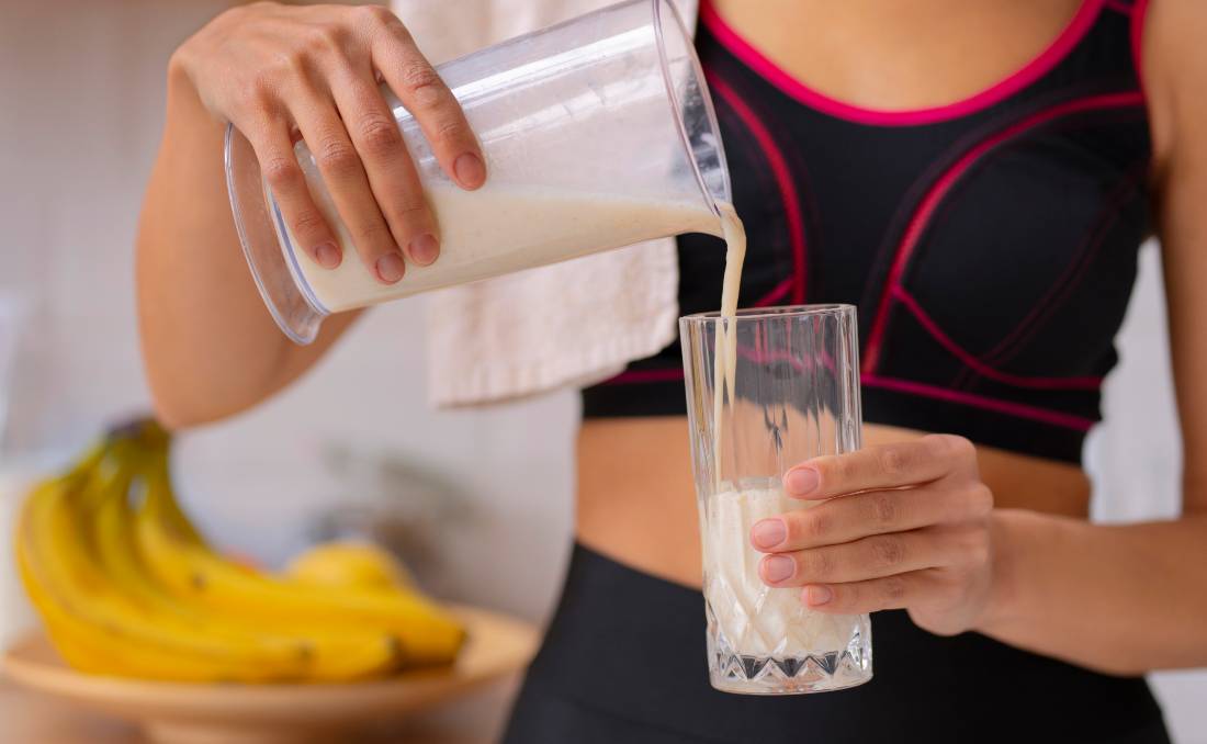 Žena sipa whey protein u čašu nakon treninga.